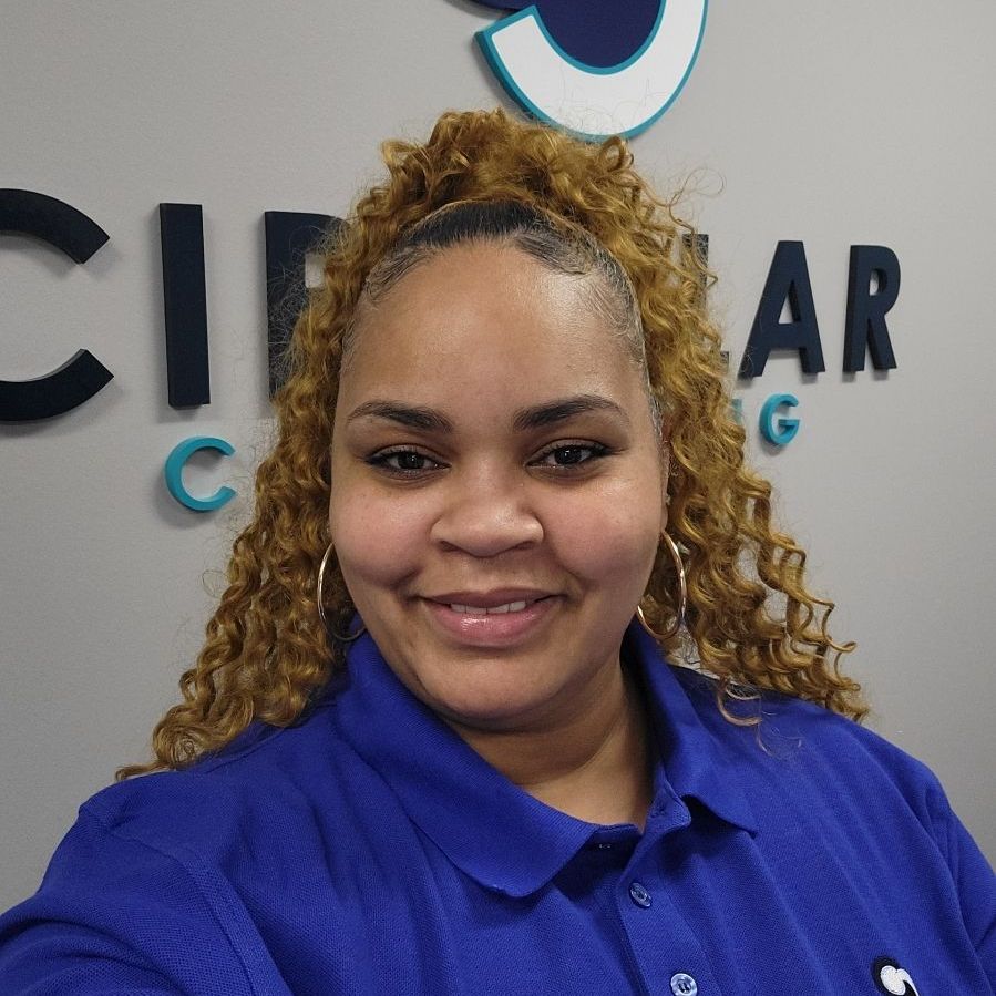 a woman in a blue shirt is smiling in front of a sign