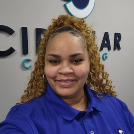 a woman in a blue shirt is smiling in front of a sign that says circular consulting