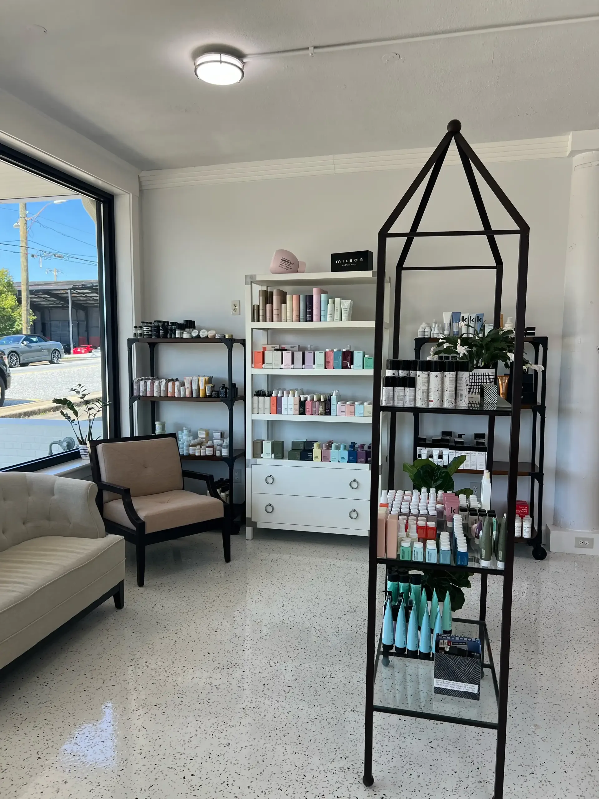 A room with a couch , chair , shelves and a window