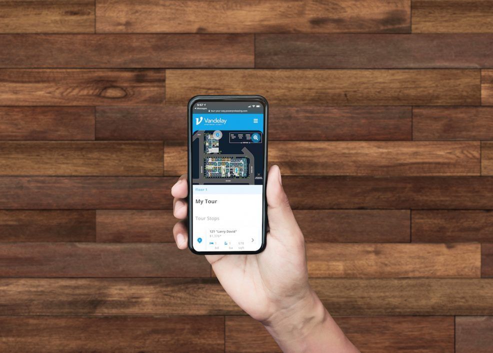 A person is holding a cell phone in front of a wooden wall.