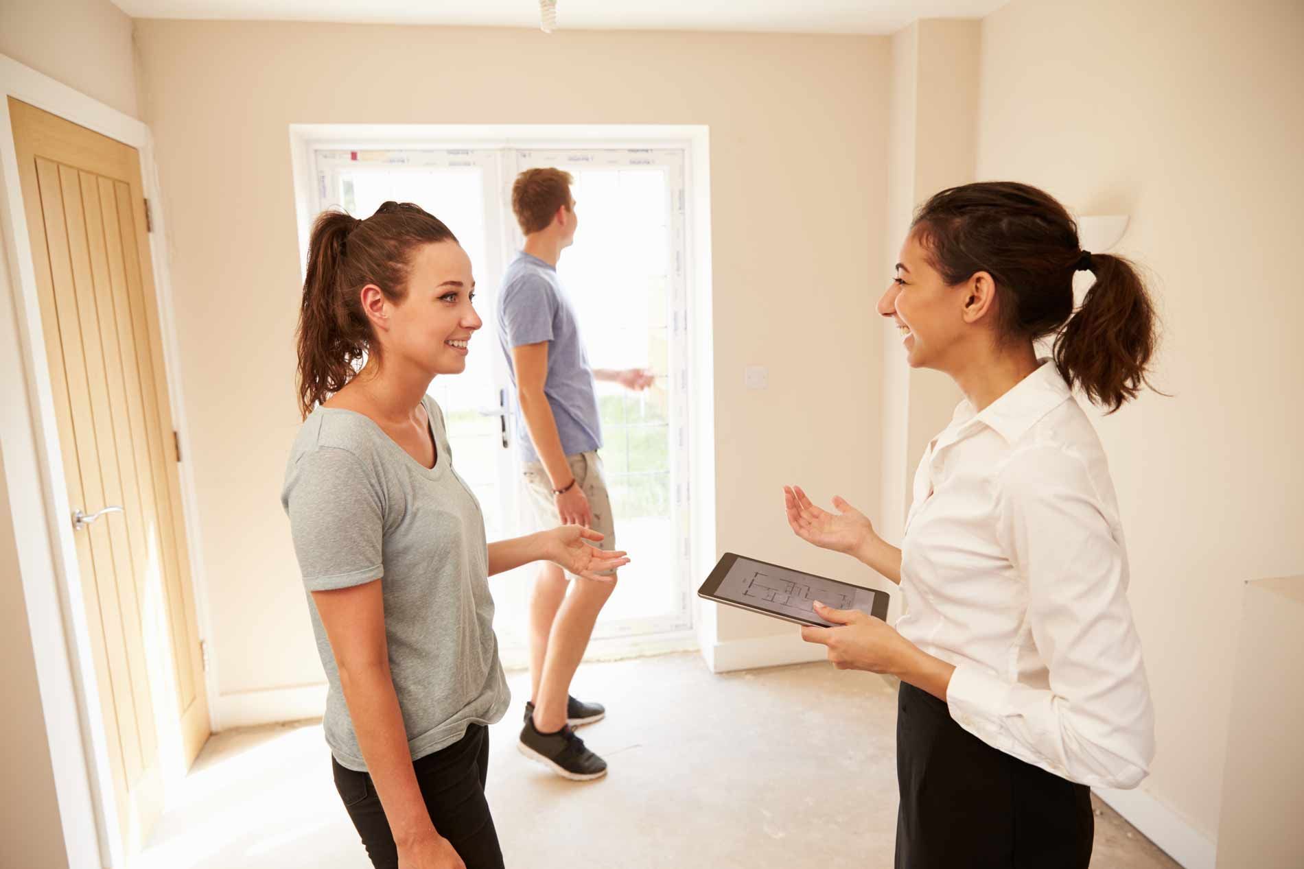A woman is talking to a man and a woman in an empty room.