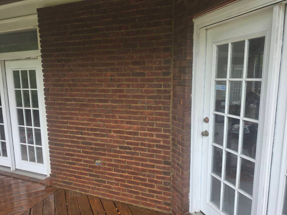 Brick porch with white French doors and wooden bench under a covered overhang