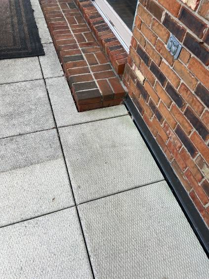Brick and concrete walkway beside a brick wall, with a raised brick step along the edge