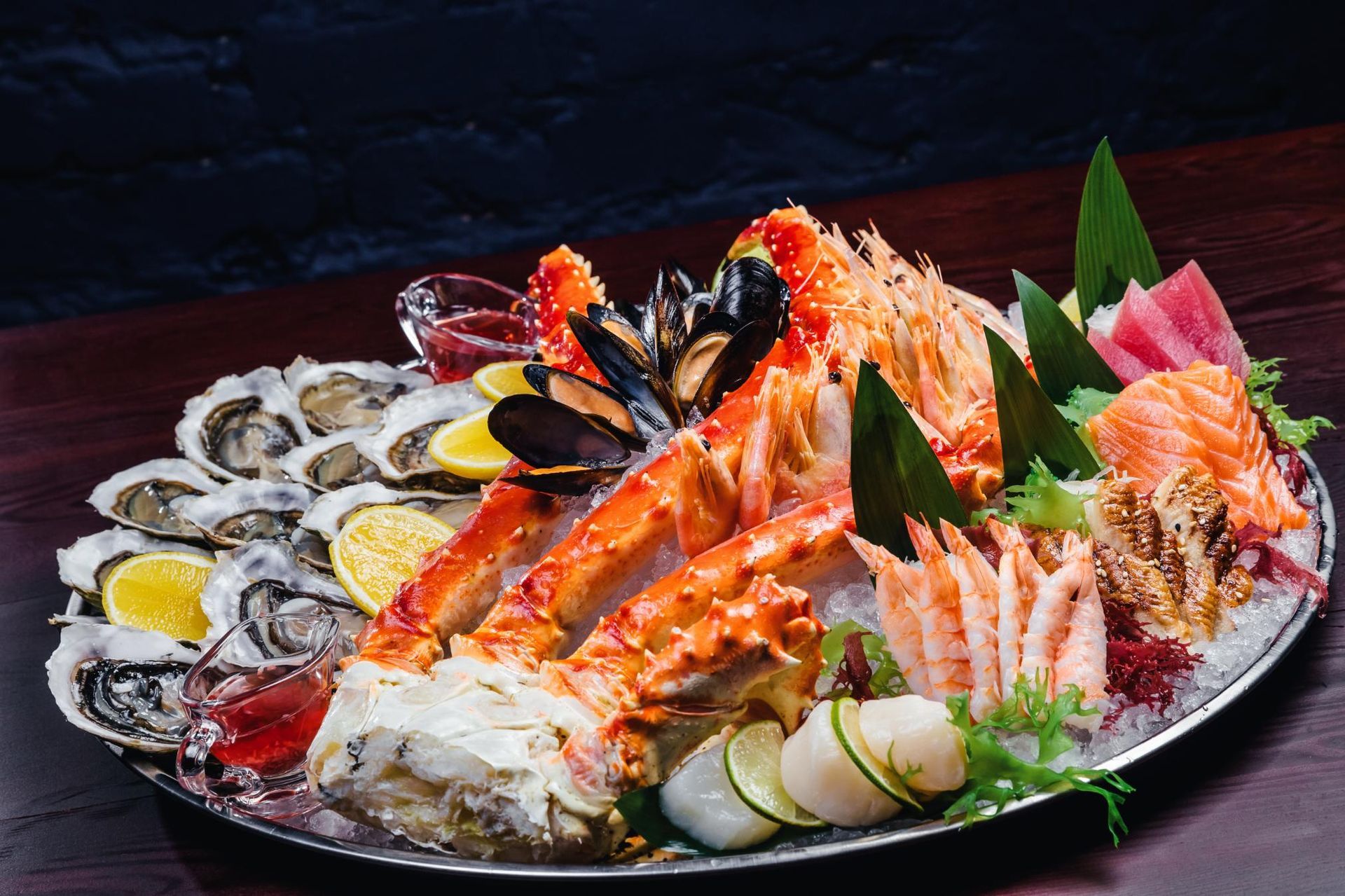 Seafood platter with crab legs, oysters, shrimp, and lemon wedges on a decorative plate