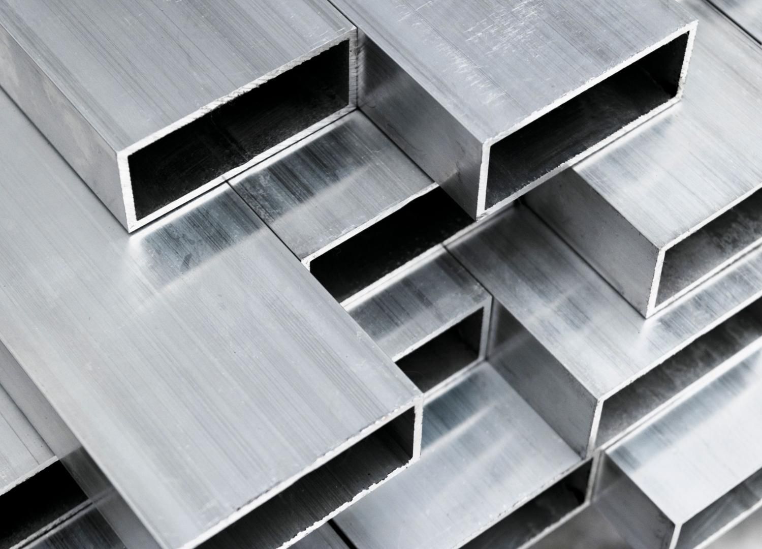 Tubes rectangulaires en aluminium argenté empilés, à centre creux, sur une surface en métal brossé