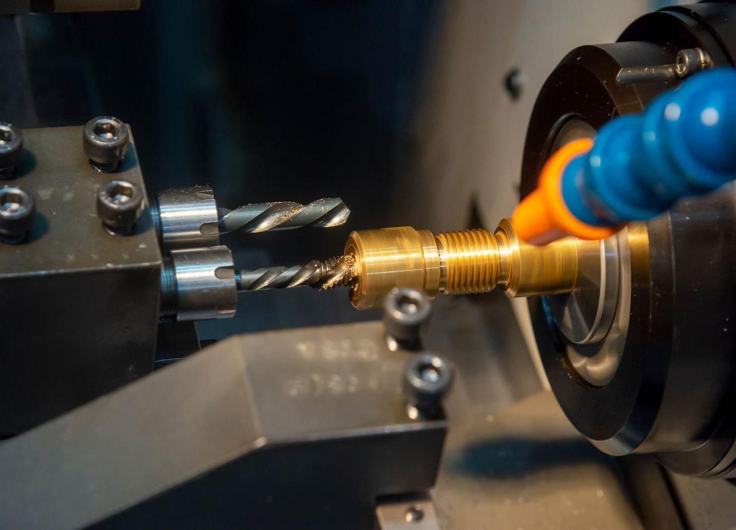 Tour CNC coupant une tige de métal doré avec un foret et une buse de refroidissement dans un atelier