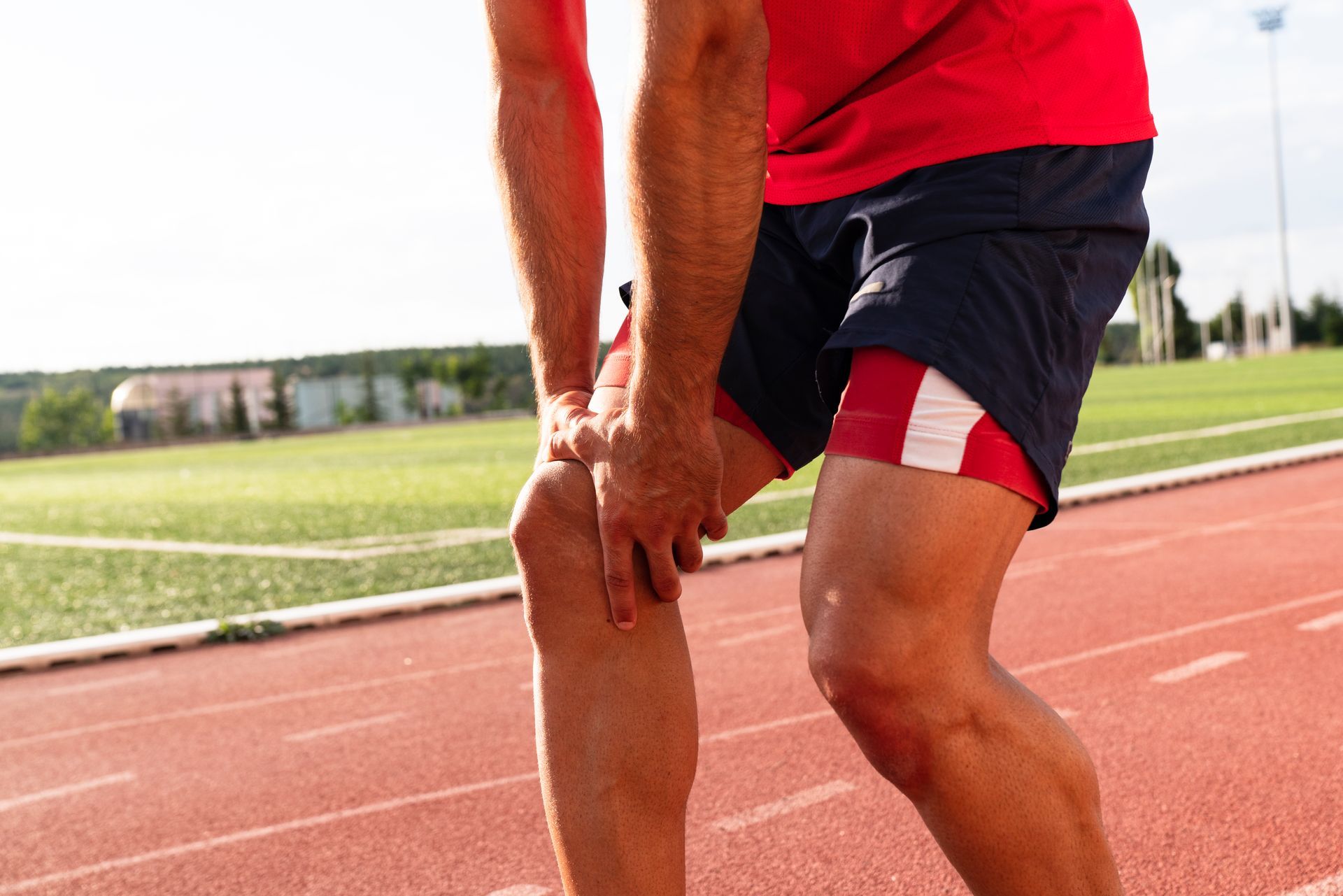 Atleta in pista che si stringe il ginocchio dolorante.