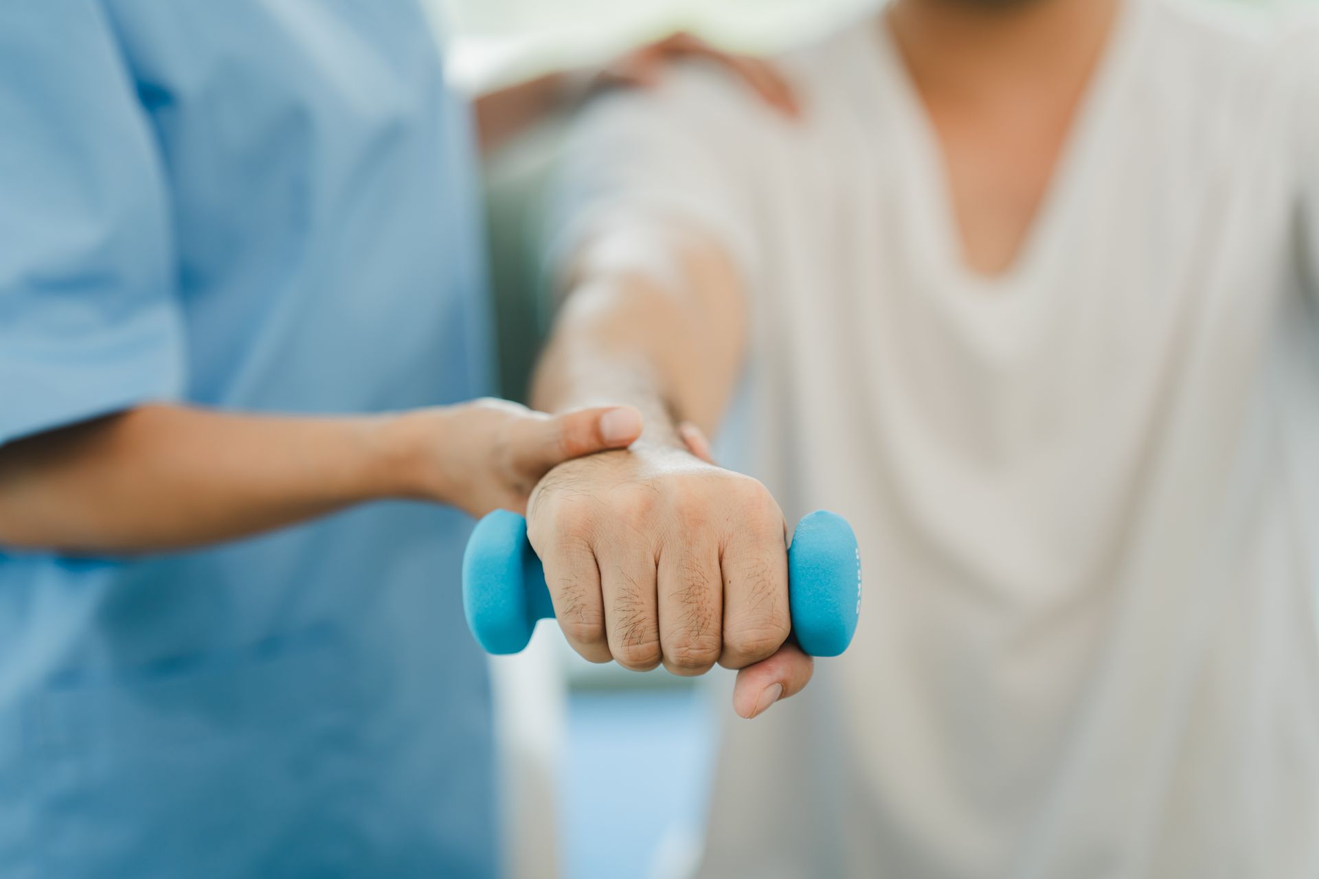 Terapista che aiuta un paziente a eseguire un esercizio con manubri blu.