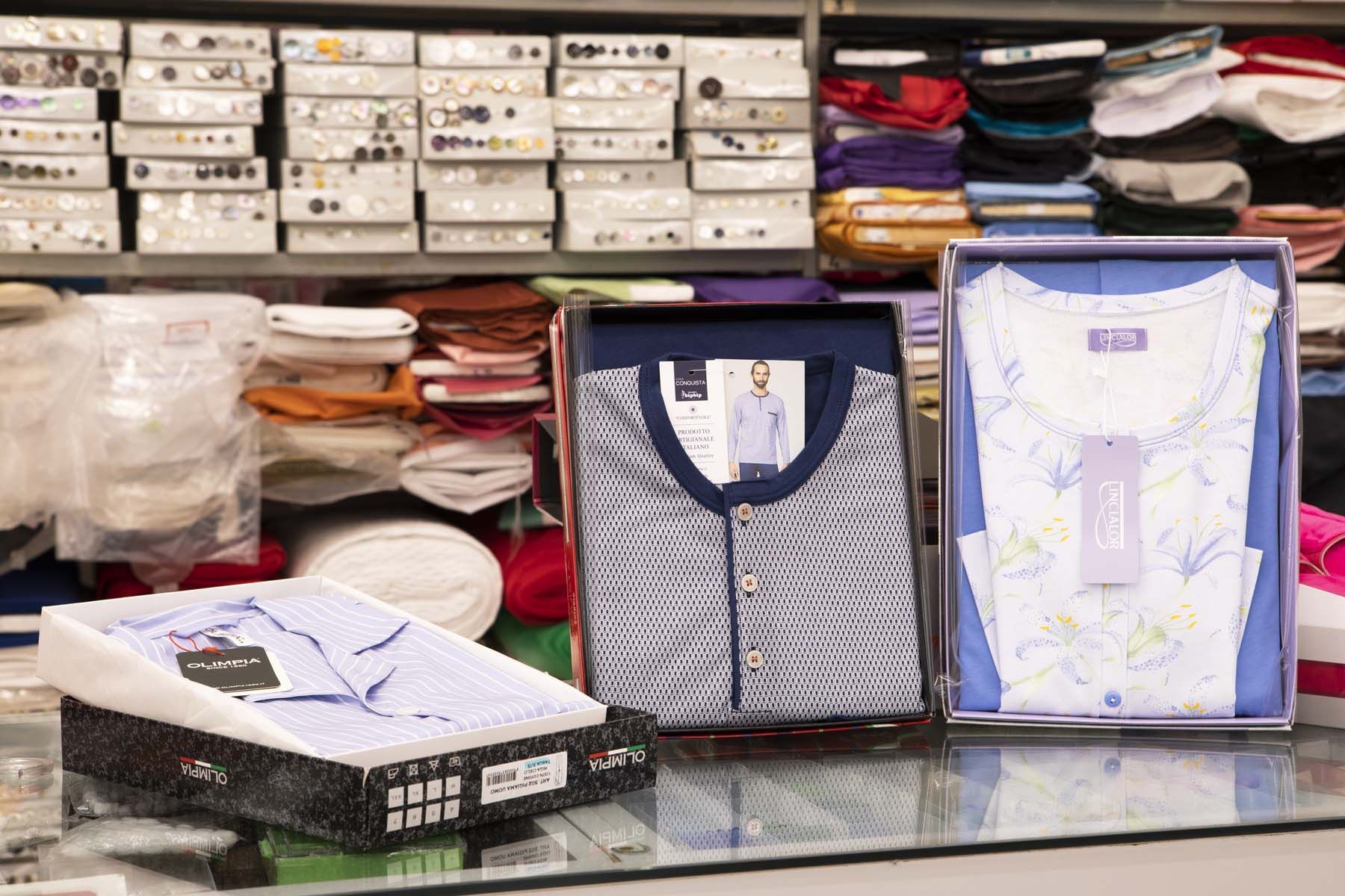 Esposizione di un negozio di abbigliamento con pigiami in scatole e scaffali pieni di articoli piegati sullo sfondo.