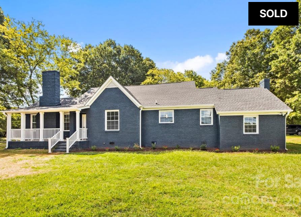 Blue single-story house with white trim and a large grassy yard, marked “SOLD”