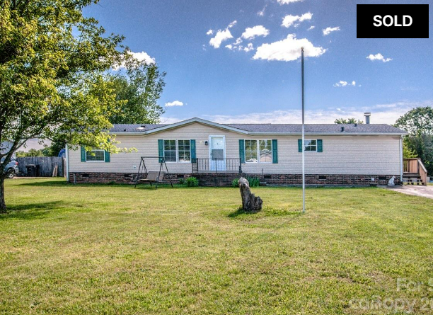 Single-story beige house with a large front lawn and a “SOLD” sign in the top right corner