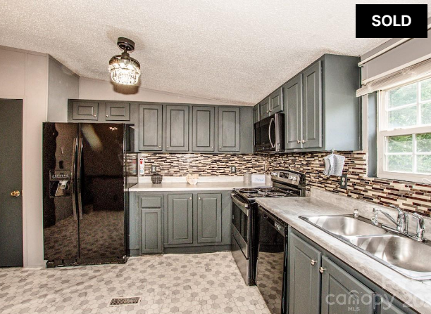Gray kitchen with black refrigerator, mosaic backsplash, and double sink; SOLD label in corner