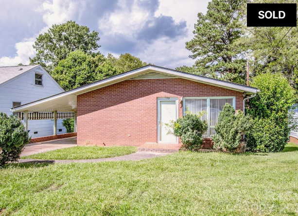 Single-story brick house with a front lawn and SOLD sign