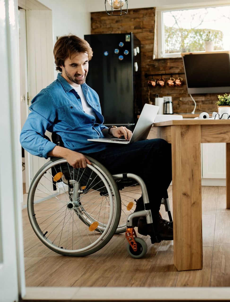 Elderly woman in wheelchair in kitchen, looking at man preparing food.