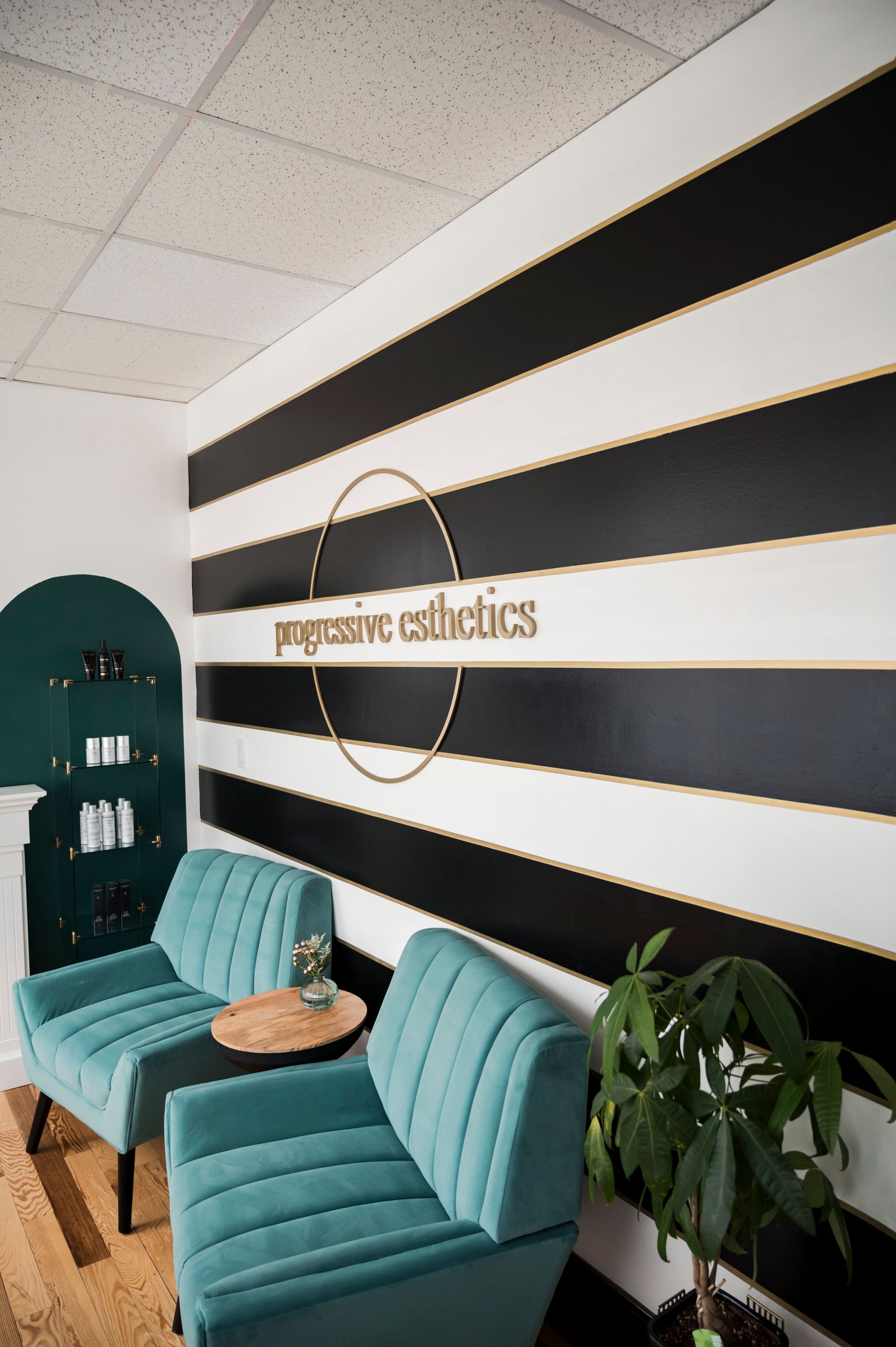 Waiting area with teal chairs, striped wall, and gold logo for 