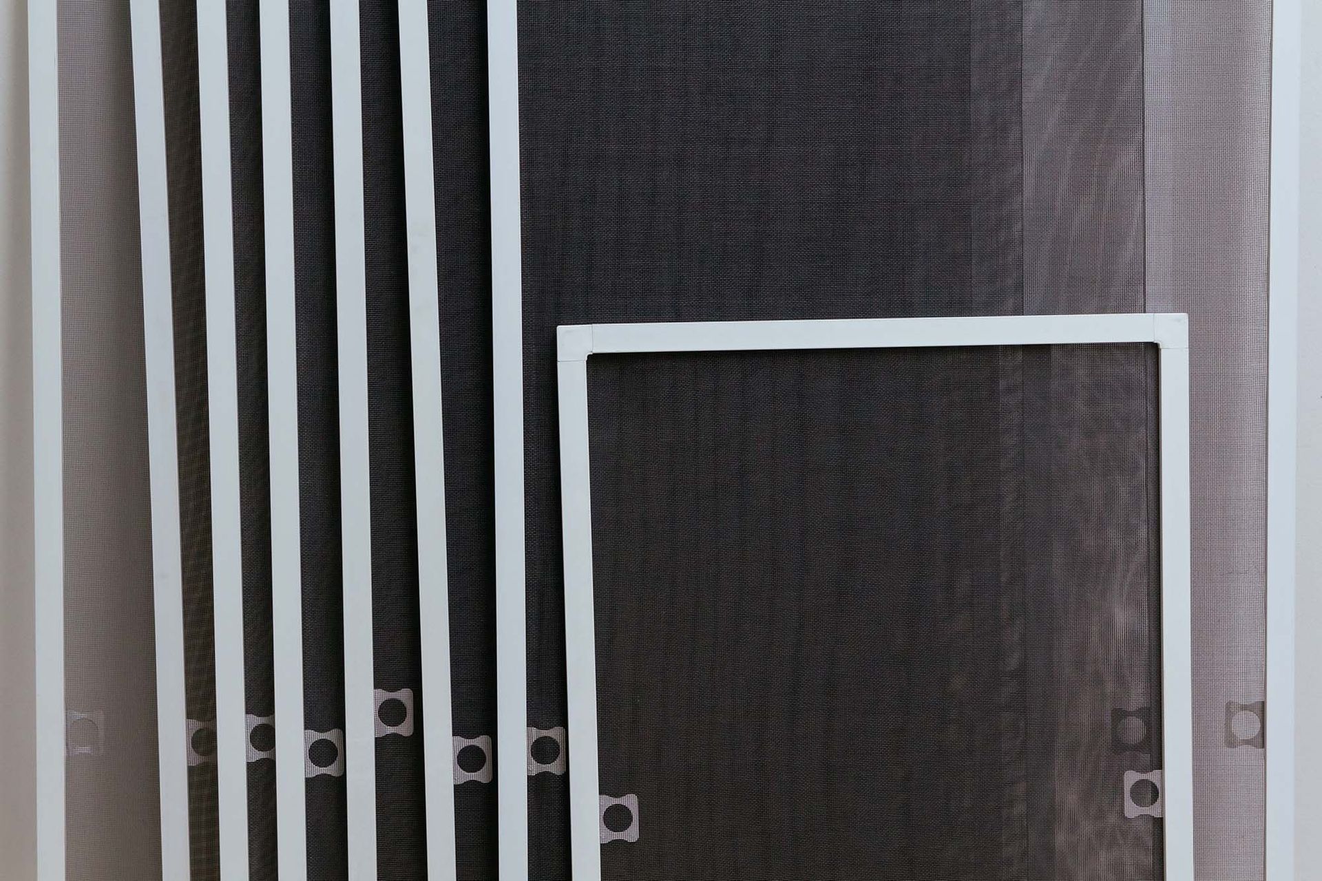 Black-and-white striped curtains beside a white-framed screen door on a dark exterior wall