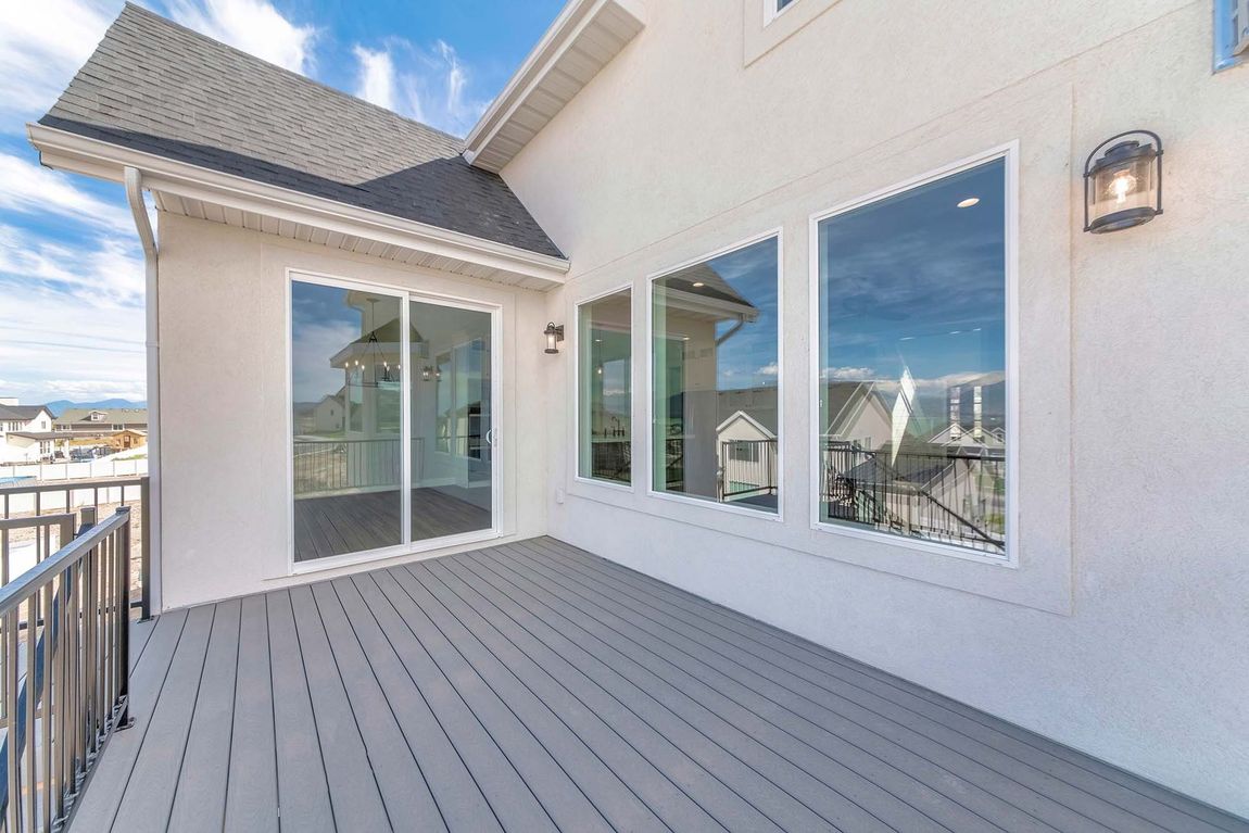 Spacious white deck with sliding glass doors, large windows, and a wall lantern overlooking a snowy neighborhood