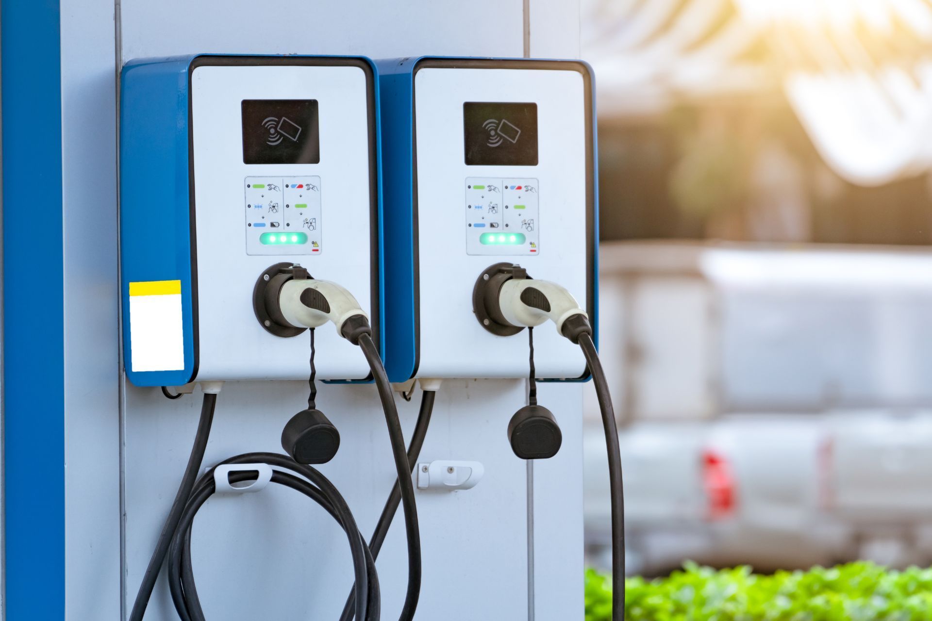 Two electric vehicle charging stations mounted on a wall, each with a plugged-in charging cable.