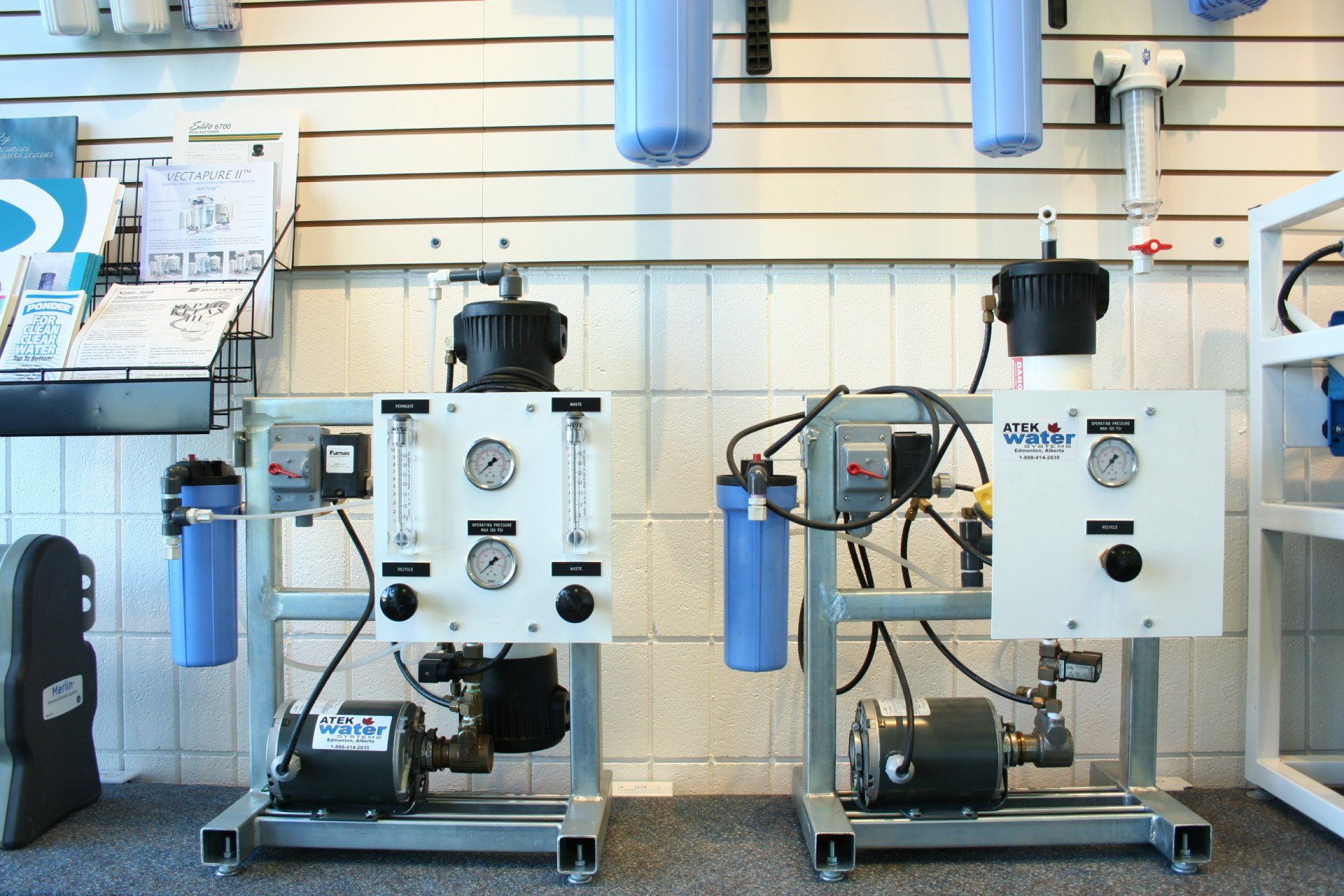 Two industrial white machines with gauges and hoses in a workshop showroom