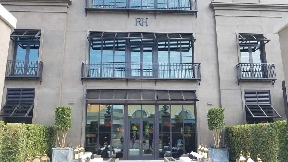 Gray building with black framed windows, doors, and awnings.