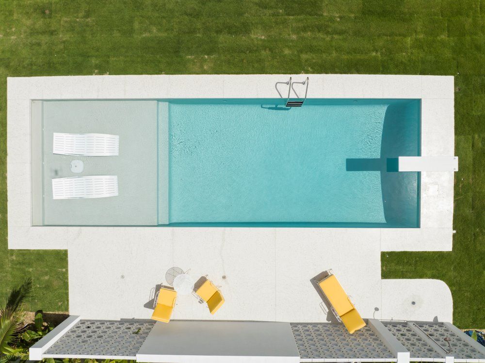 An Aerial View of a Large Swimming Pool Surrounded by Lawn Chairs — Beith Building & Developments Pty Ltd In Burleigh Heads, QLD