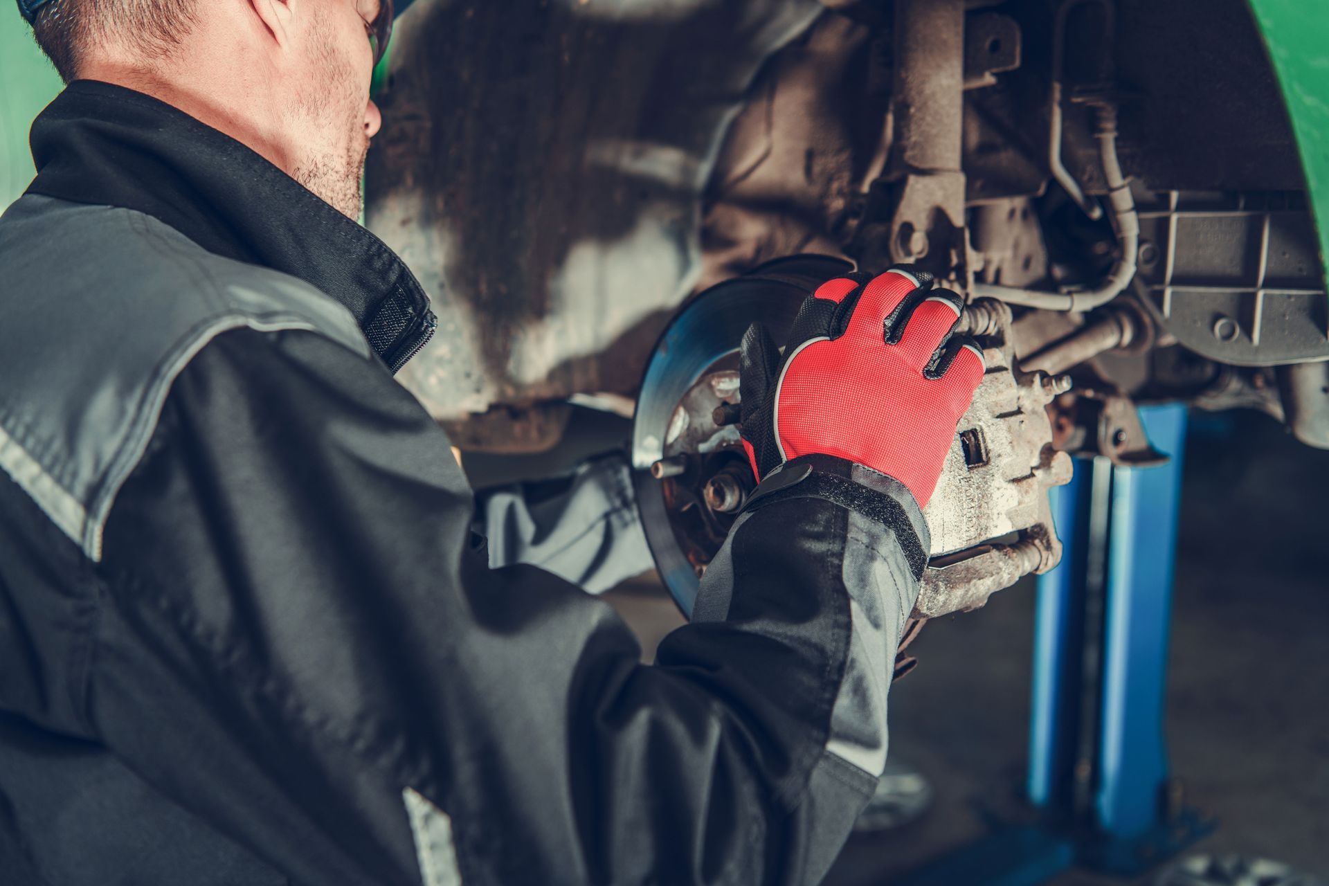 a man is working on a car on a lift in a garage .