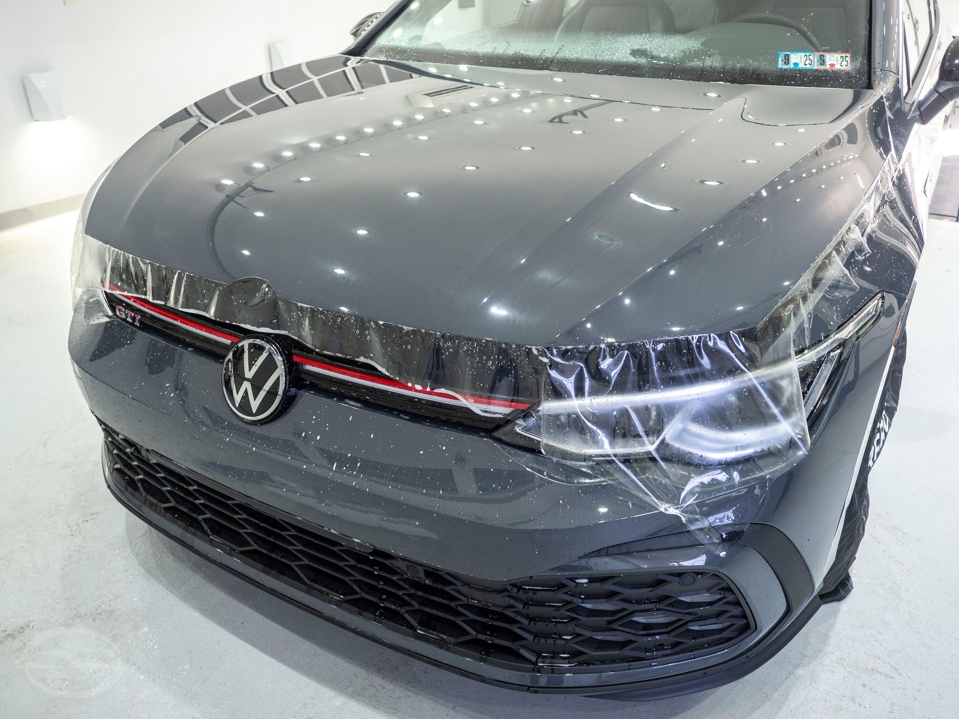 A black volkswagen golf gti is covered in plastic wrap.