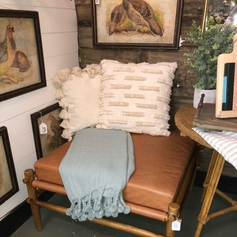 Cozy corner bench with tan cushion, white pillows, blue throw, framed bird art, and a small table with flowers.