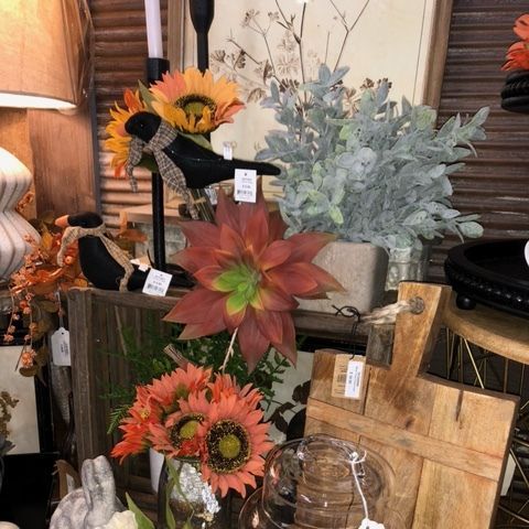 Autumn floral arrangement with sunflowers, red leaves, and rustic wooden decor in a shop display