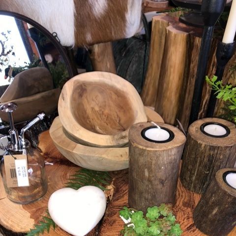Rustic wooden decor with a carved chair, stump candles, white heart ornament, and greenery on a table