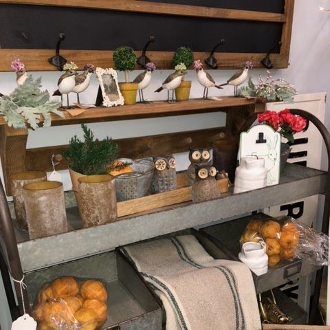 Rustic fall decor shelf with white birds, pumpkins, candles, and greenery in a cozy display