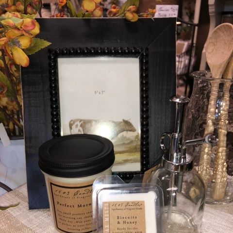Decorative autumn display with framed photo, candles, jars, and wooden utensils on a table