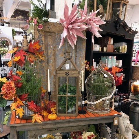 Fall autumn porch display with pumpkins, lanterns, colorful leaves, and birdcages under a wooden bench