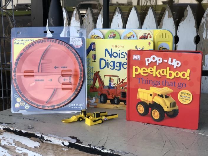 Children’s books and toy construction vehicles displayed on a bench outdoors