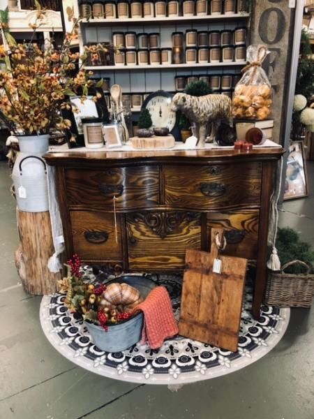 Rustic wooden dresser styled with pumpkins, lanterns, and fall decor in a shop display