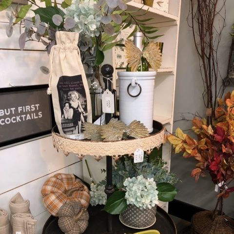 Decorative shelf display with flowers, bottles, and autumn accents in a cozy home setting