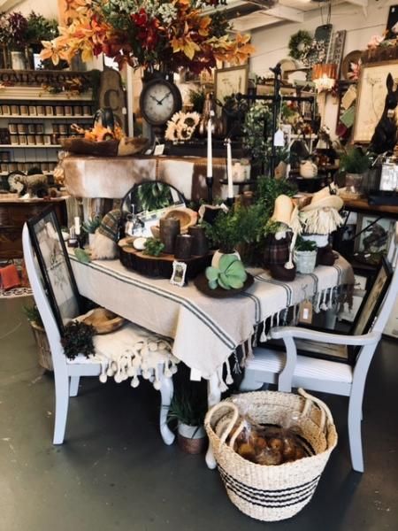 Cozy farmhouse dining room with white table, black-and-white decor, greenery, and autumn floral arrangements