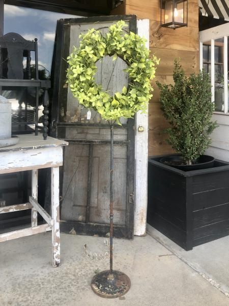 Green wreath on a metal stand outside a rustic storefront doorway