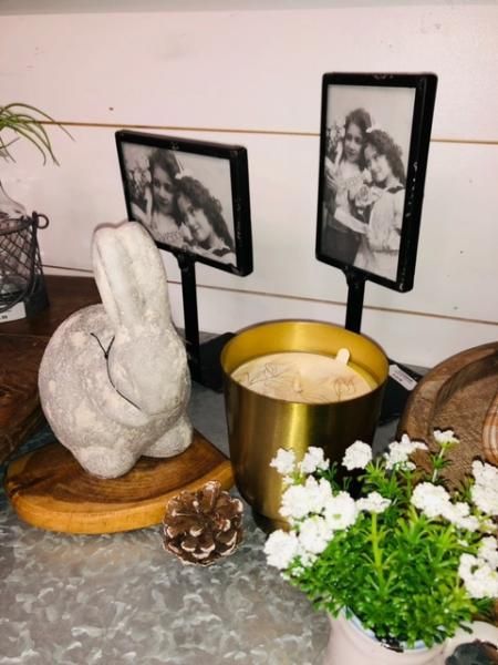 Candle and white floral arrangement with framed black-and-white photos on a tabletop display