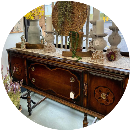 Antique wooden sideboard with decorative vases and a topiary centerpiece in a bright room