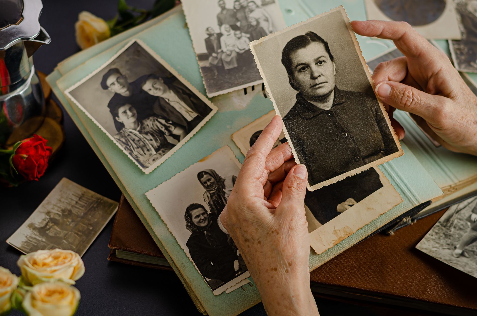 Hands sorting vintage black-and-white photos in an open album on a table