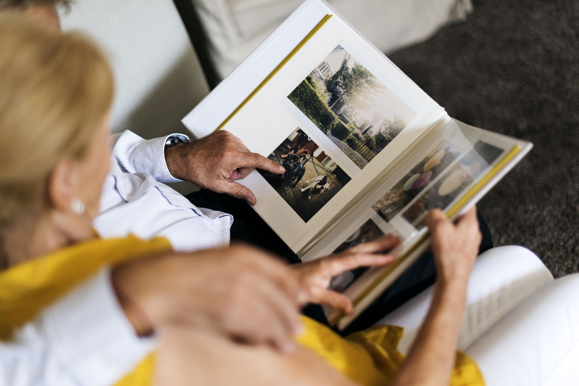 Two people sit on a couch looking through a photo album together.