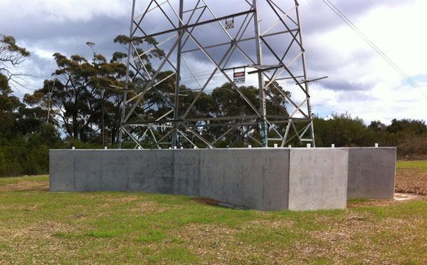 A power tower is sitting in the middle of a grassy field