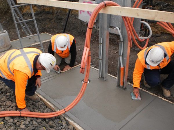 Three construction workers are working on a concrete surface