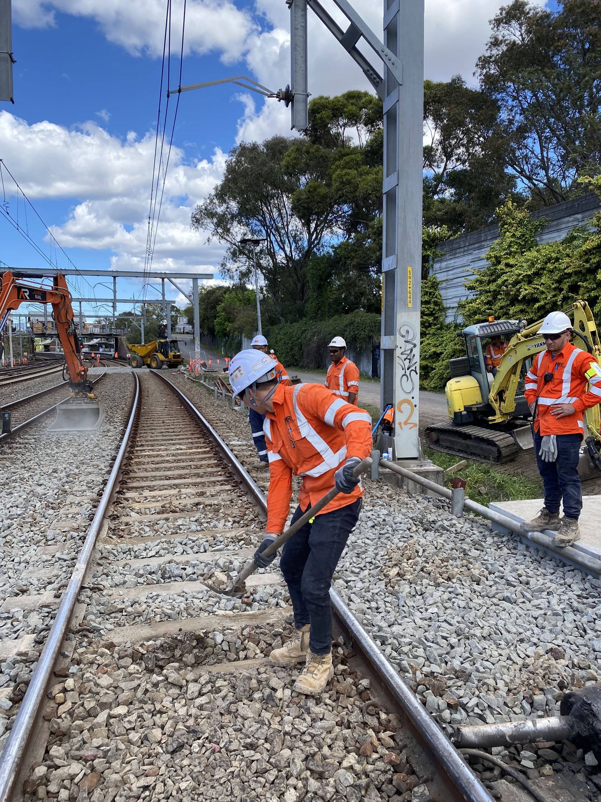 A group of construction workers are working on train tracks.