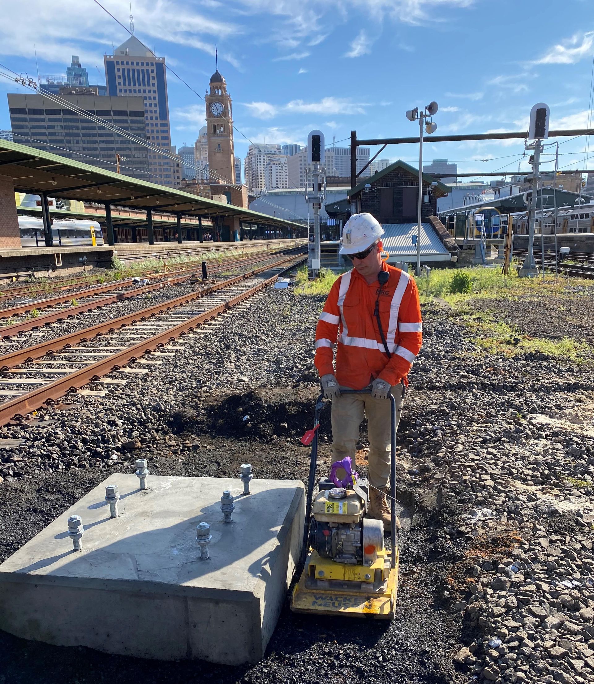 A man is standing on a concrete block next to a train track.