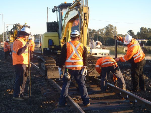 A group of construction workers are working on train tracks