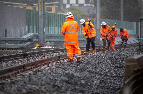 A group of construction workers are working on train tracks.