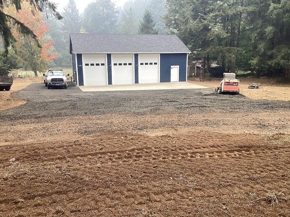 A truck is parked in front of a garage with three garage doors.