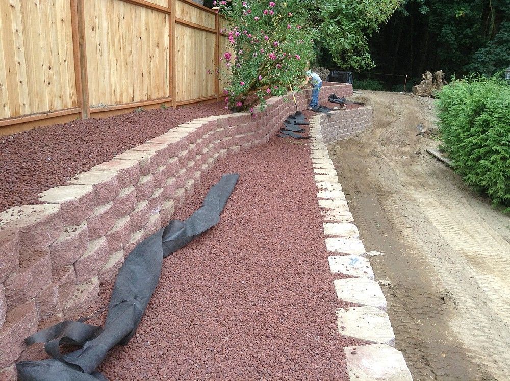 A brick wall is being built next to a dirt road.